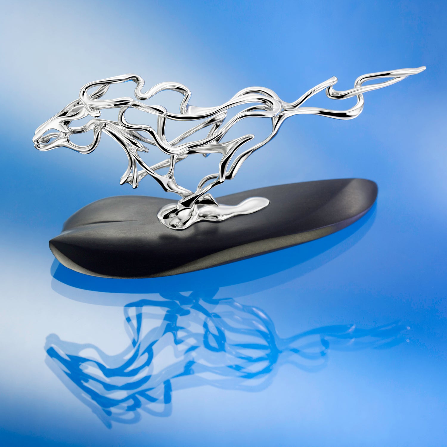 Silver horse sculpture on a black base against a beige background