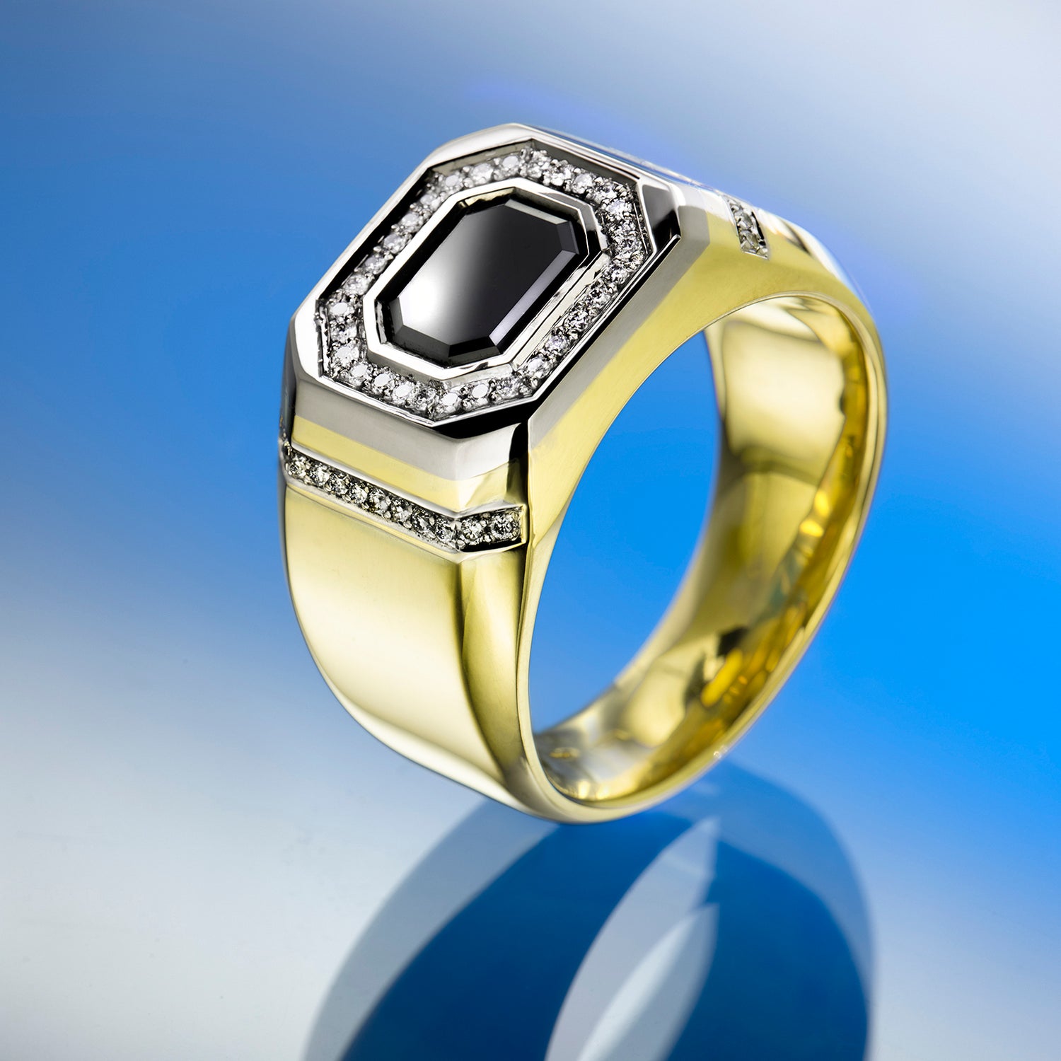 Gold ring with a black gemstone and diamond accents on a beige background