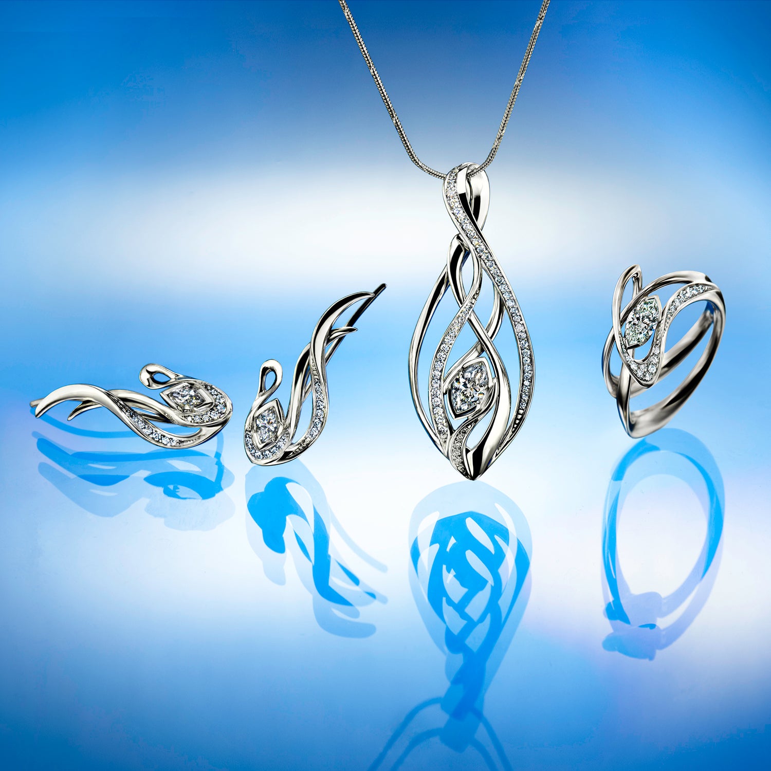 Silver jewelry set with necklace, earrings, and ring on a reflective blue surface