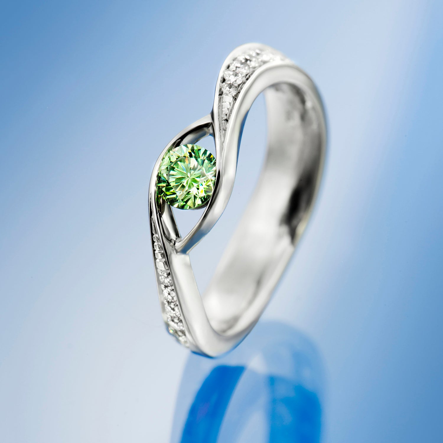 Silver ring with a green gemstone on a beige background