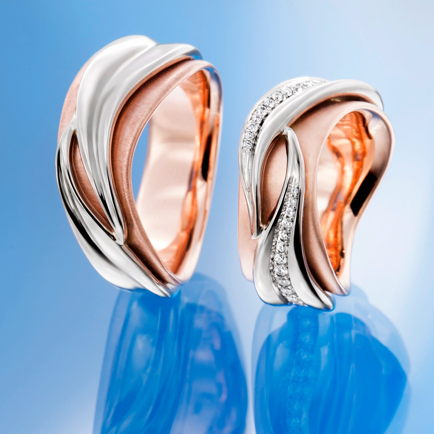 Two rose gold and silver earrings with diamond accents on a beige background