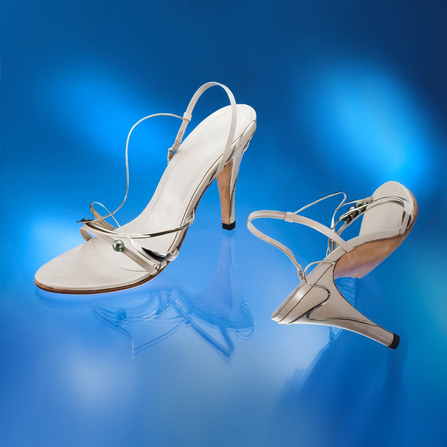 White high-heeled shoes on a beige reflective surface